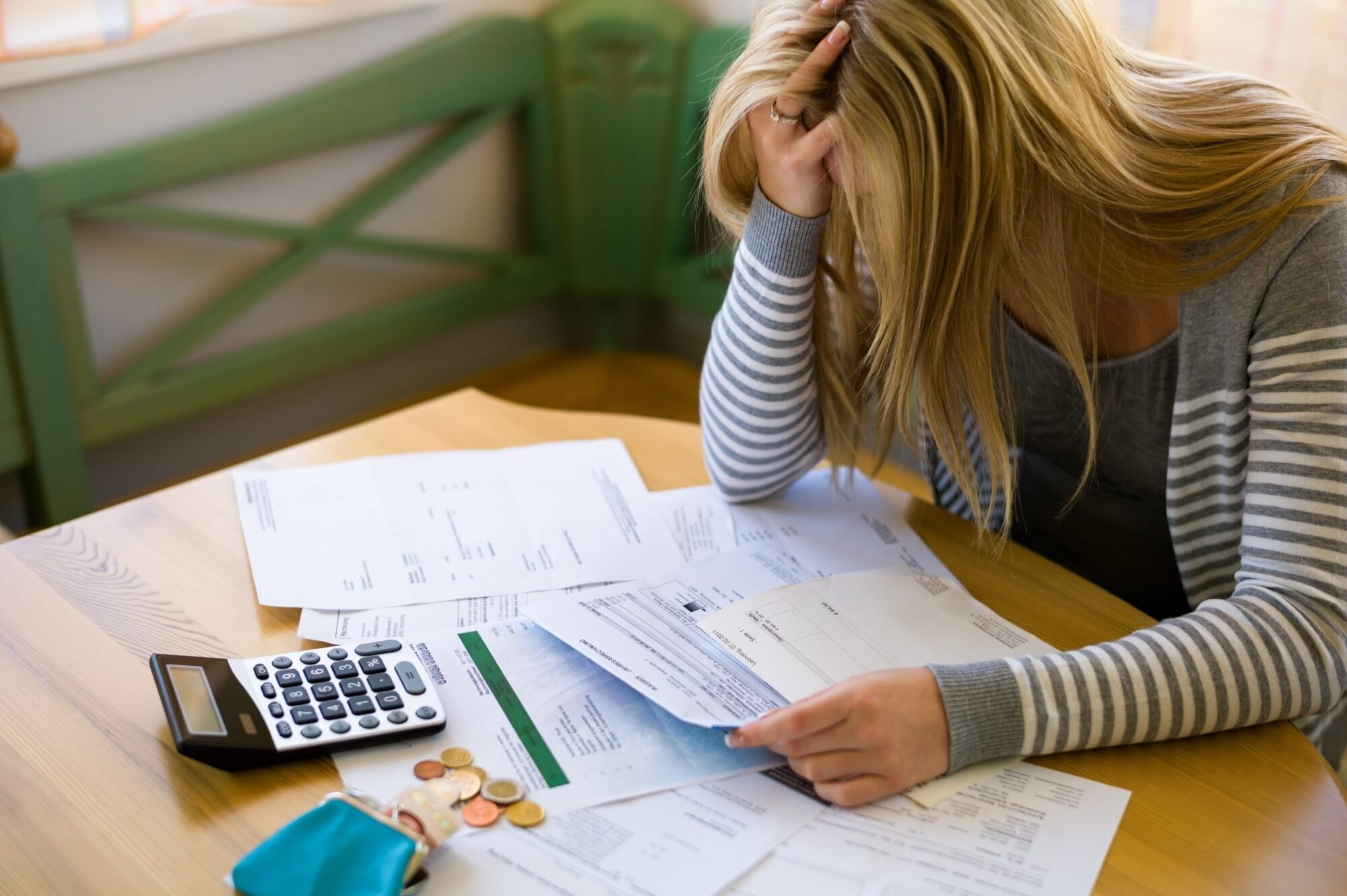 A woman holding her head in her hands looking at billsl to show financial stress, wanting Money Services Lincoln Park.
